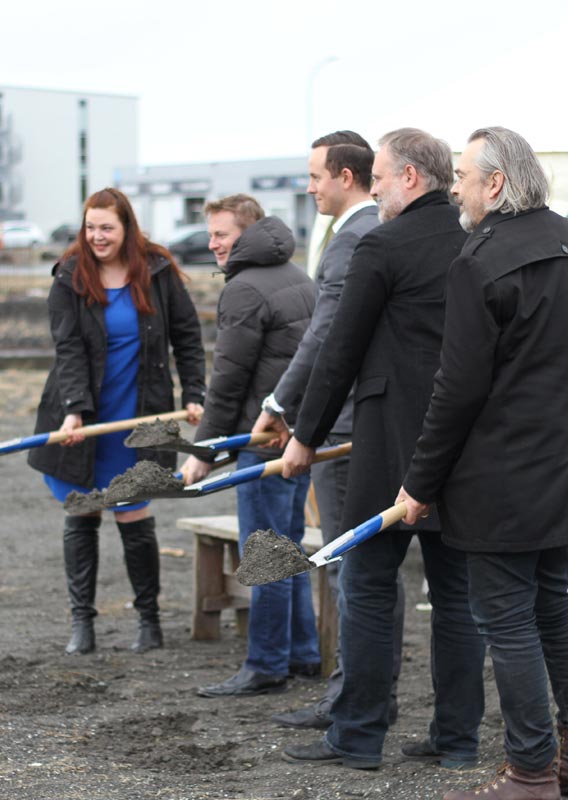 Five people stand with shovels of dirt at the FlyOver Iceland groundbreaking ceremony.