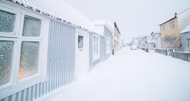 A view down a city street of houses covered in snow and ice.