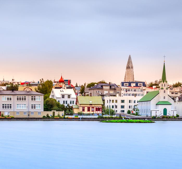 The sea shore in Rekyjavík, including tall churches and colourful buildings.