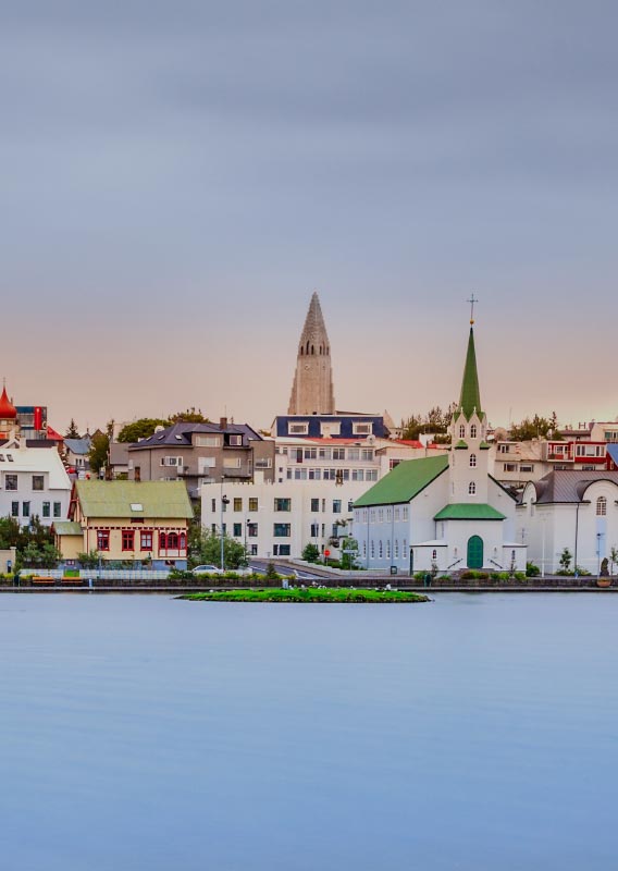 The sea shore in Rekyjavík, including tall churches and colourful buildings.