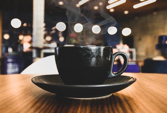 A coffee cup steaming on a wooden table.
