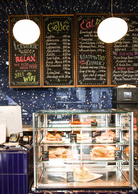 A cafe counter showing pastries and chalkboard menu