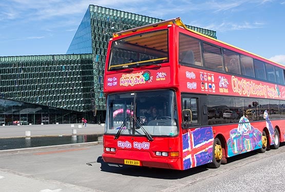 A red tour bus outside the Harpa Concert Hall