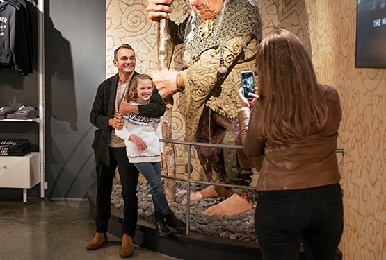 A dad and kid get their photo taken at a troll statue.