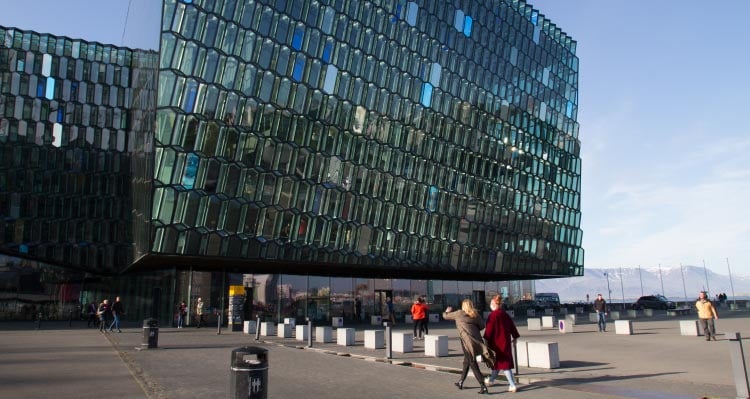 A pair of people walk towards a glass-walled modern building.