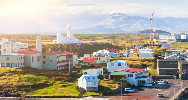 A village of colourful buildings sits among rocky and grassy terrain.