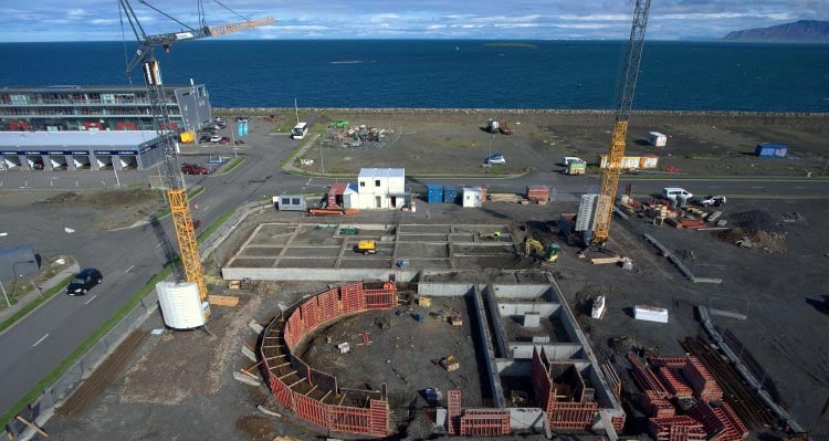 A new building beginning construction in a plot of land near the sea.