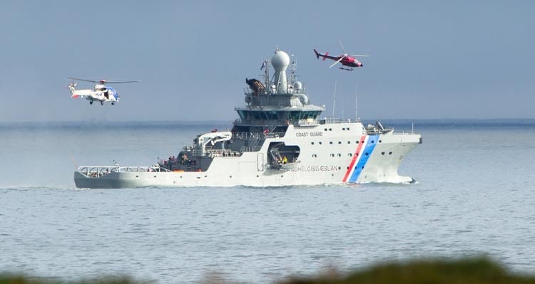 Two helicopters fly around an Icelandic Coast Guard ship.