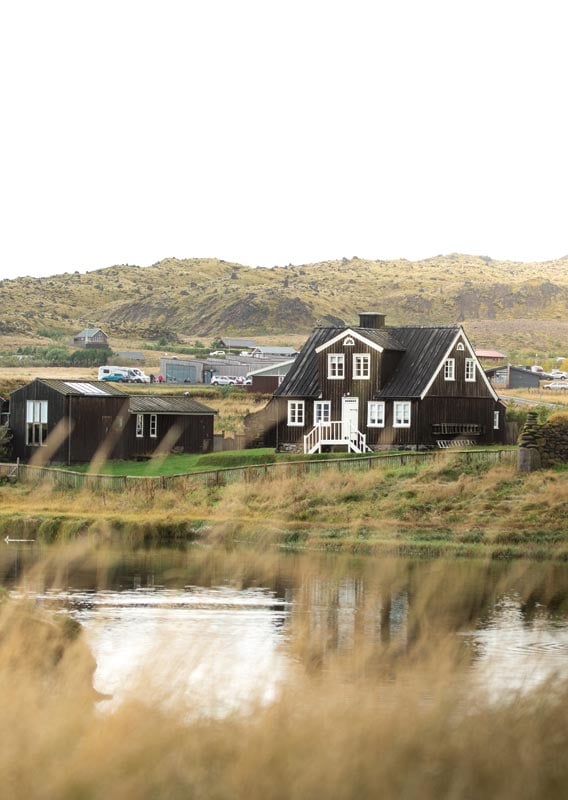 Þorp sem stendur við árbakka og græn engi