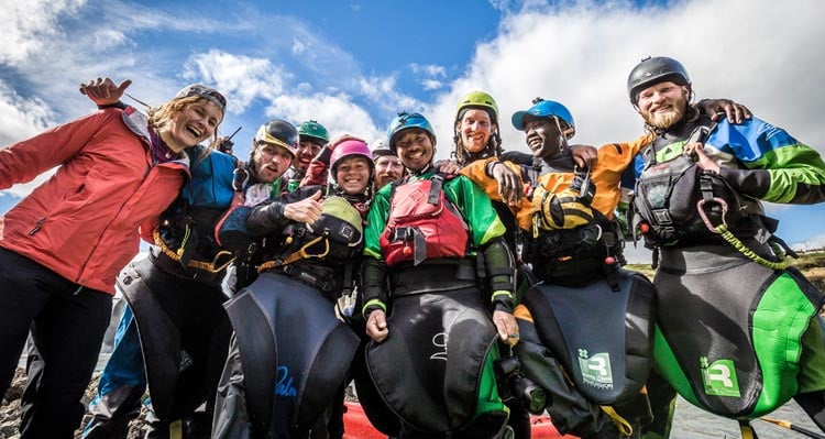 A group of kayakers celebrate their accomplishments.