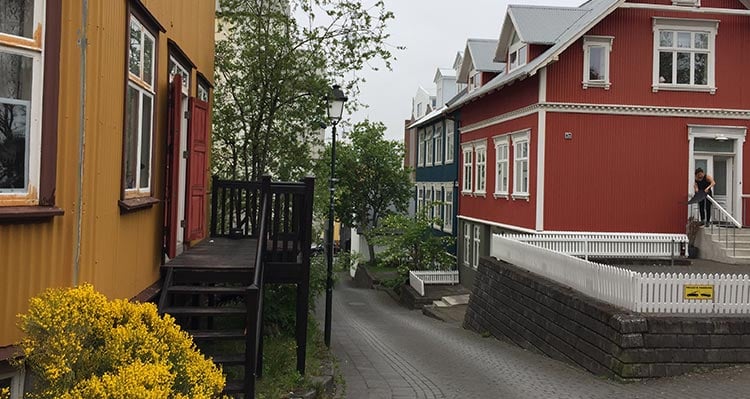 A narrow brick road between colourful buildings.