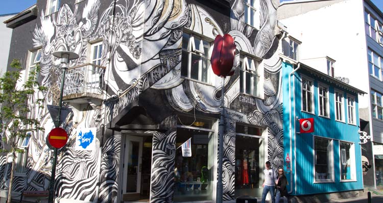 A building covered in a black and white painting at a street corner