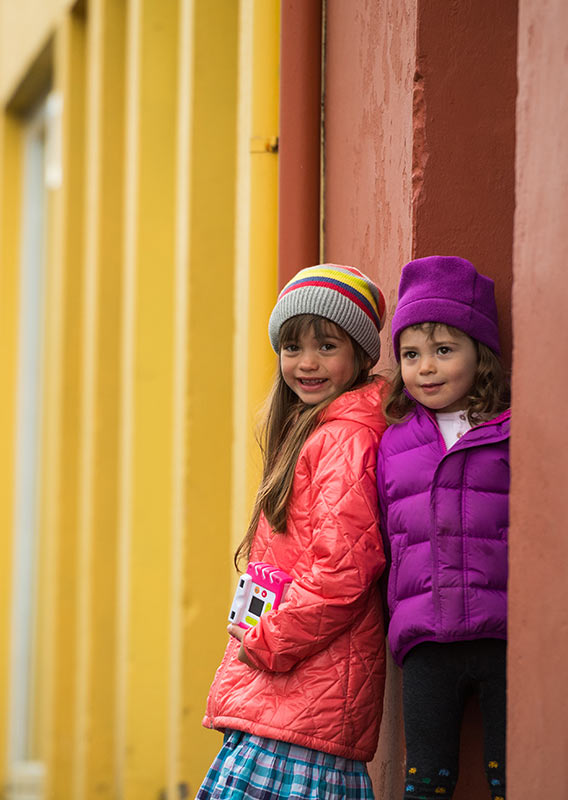 Two young girls pose among brightly coloured buildings of Reykjavík