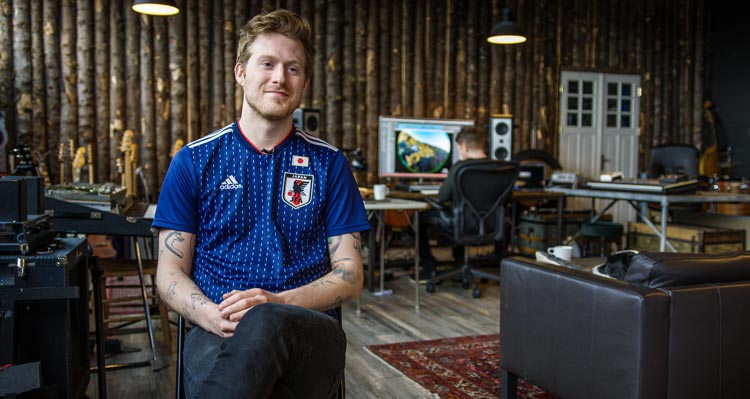 A man in blue sits in a music studio.