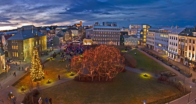 A city square decorated for Christmas with lights on trees.