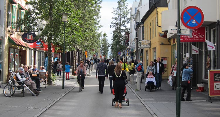 People walk down a narrow pedestrian street between colourful buildings.