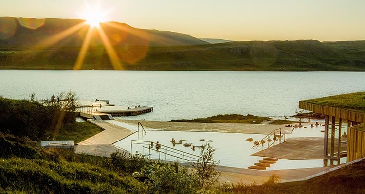 A hot pool and dock located against clear water.