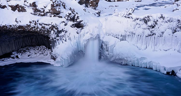 The waterfall Aldeyjarfoss. A waterfall crashes through icy cliffsides.