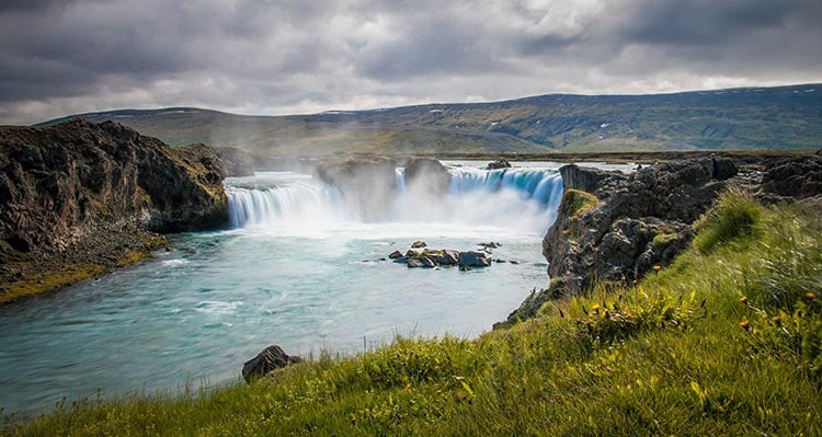 The waterfall Goðafoss. A wide waterfall rushes into a big river.