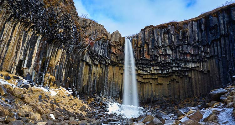 The waterfall Svartifoss. A tall waterfall between geometric rock columns.
