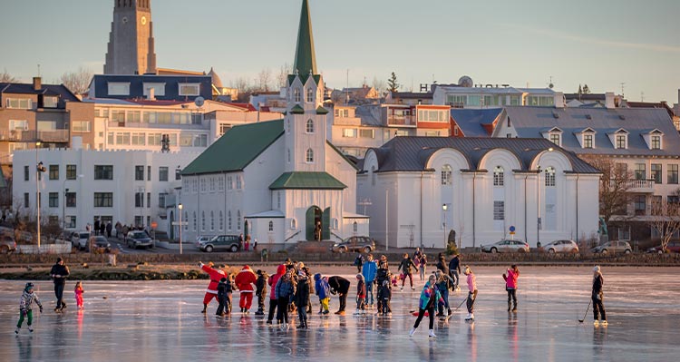 A group of people ice skate on a frozen pond.