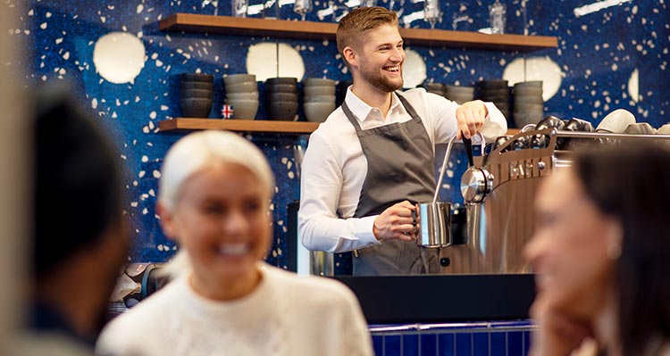 A coffee shop barista works at an espresso machine.