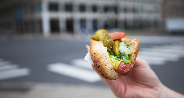 Image of a hand holding a Chicago style hot dog.